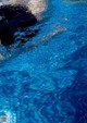 A person swimming in a blue pool with water ripples.