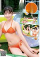 A woman in an orange bikini sitting on an inflatable pool.