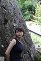 A woman standing in front of a large rock wall.