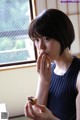 A woman eating a piece of food in front of a window.