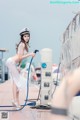 A woman in a sailor's hat is using a hose to clean a boat.