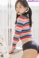 A woman in a striped sweater and black panties posing for a picture.