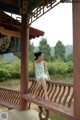 A woman sitting on a wooden bench in a pavilion.