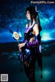A woman in a purple and black outfit holding a wand.
