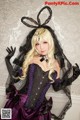 A woman dressed in a black and purple corset and veil.