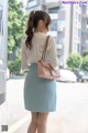 A woman in a white shirt and blue skirt is walking down the street.