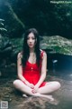 A woman in a red dress sitting in the water.