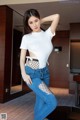 A woman in a white shirt and blue jeans posing for a picture.