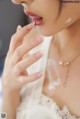 A woman in a white dress is putting on lipstick.