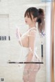 A woman in a white lingerie standing in a shower.