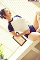 A woman in a blue and white shirt is sitting on a table.