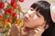 A woman in a straw hat smelling a bunch of tomatoes.