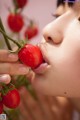 A woman is eating a tomato from a vine.