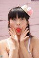 A woman with a straw hat and a red lollipop in her mouth.