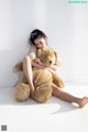 A young girl sitting on the floor with a large teddy bear.