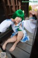 A woman with green hair sitting on a wooden bench.