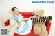 A woman sitting on a red couch with two teddy bears.