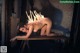 A naked woman laying on a table with candles on her head.