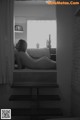 A naked woman sitting on a window sill in a bedroom.