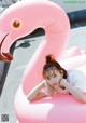 A woman laying on top of a pink flamingo float.