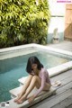 A woman sitting on the edge of a swimming pool.