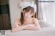 A woman in a bathtub with a white towel on her head.