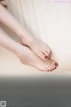 A woman's feet with red nail polish on a white couch.