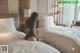 A woman sitting on a bed in a hotel room.