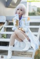 A woman in a white coat and white boots sitting on some steps.