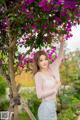 A woman standing in front of a tree with purple flowers.