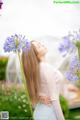 A woman standing next to a bunch of purple flowers.