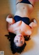 A woman in a black bikini laying on the floor.