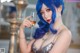 A woman with blue hair holding a glass of wine.