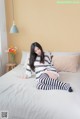 A woman sitting on a bed in a bedroom.