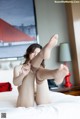 A woman sitting on top of a bed with her legs up.