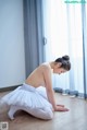 A woman in a white tutu sitting on the floor.