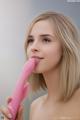 A woman holding a pink dildo in her mouth.