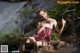 A woman sitting on a rock in front of a waterfall.