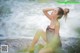 A woman sitting on a rock in the water.