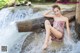 A woman sitting on a log in the water.