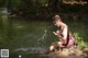 A woman sitting on a rock in the water.