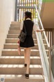 A woman in a black skirt and a white shirt is walking up some stairs.