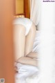 A woman in a white panties is sitting on a bed.