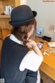 A woman sitting at a desk using a cell phone.