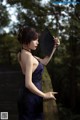 A woman in a blue dress holding a black fan.