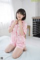 a woman sitting on top of a bed wearing a pink pajamas