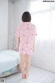 A little girl standing in front of a bed wearing a pink polka dot pajamas.