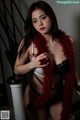 A woman wearing a red feather boa and black lingerie.