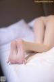 A woman laying on a bed with her bare feet on the bed.