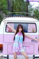 A woman standing in front of a pink van.